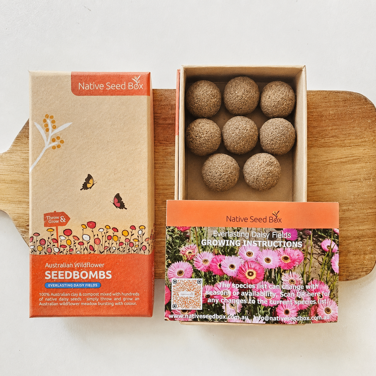 Native Seed Box Seedbombs Australian Wildflower Growing Instructions Seedbomb box shown open with eight natural seedbombs inside, alongside the retail packaging on a wooden board over a white background.